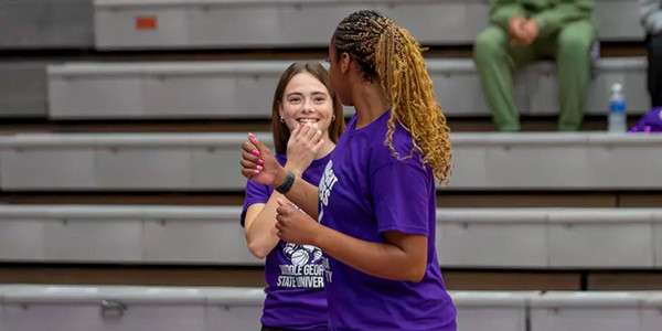 Two MGA women's basketball players smile during warm ups